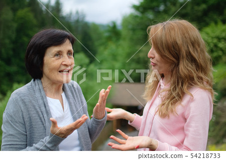 Beautiful women, two generations, mother and daughter are communicating outside in front of a 54218733