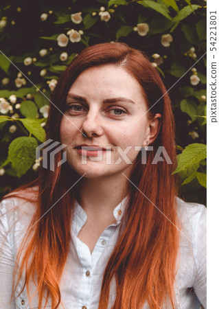 Red haired girl smiling at the camera in the botanical garden 54221801