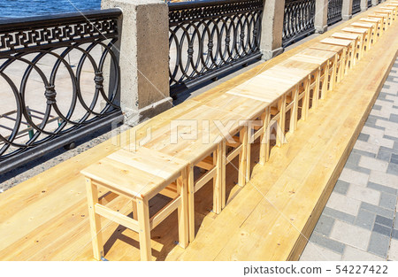 Wooden backless stools stand in a row on the Wooden backless stools stand in a row on the 54227422
