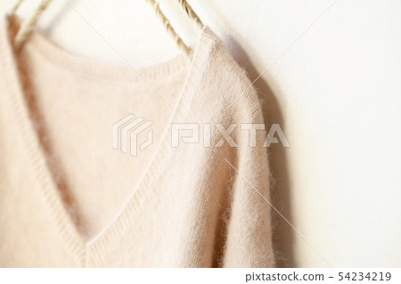 Close-up of the shoulders and collar of a light pink sweater on a white background and hanger Close-up of the shoulders and collar of a light pink sweater on a white background and hanger 54234219
