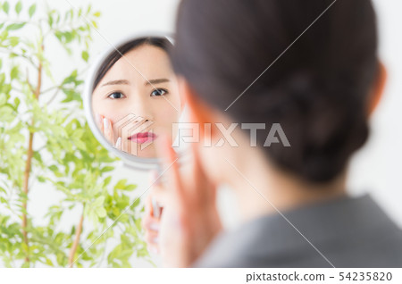 Woman looking at a mirror (business) 54235820