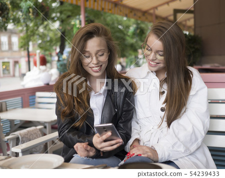 twi girls shareing secrets, while sitting at a cafe. Funny and shoking. 54239433