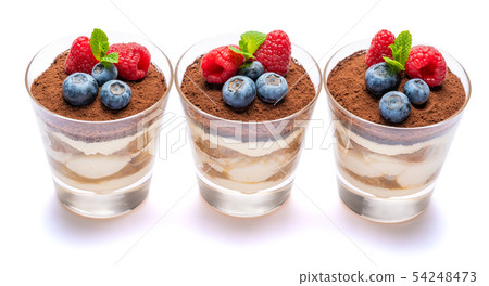 Classic tiramisu dessert with blueberries and raspberries in a glass isolated on a white background Classic tiramisu dessert with blueberries and raspberries in a glass isolated on a white background 54248473