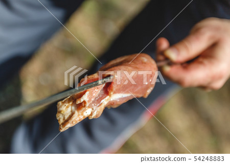 man stringing meat on a skewer. Close-up. 54248883