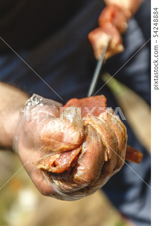 man stringing meat on a skewer. Close-up. man stringing meat on a skewer. Close-up. 54248884