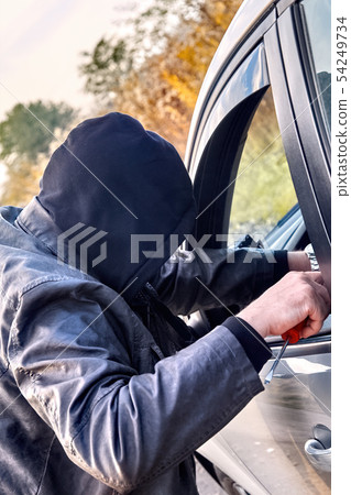 Thief wearing black clothes and leather coat stealing a car Thief wearing black clothes and leather coat stealing a car 54249734