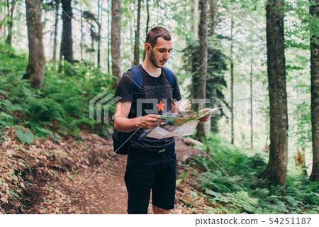 Hiker using a map to locate the destination in forest Hiker using a map to locate the destination in forest 54251187