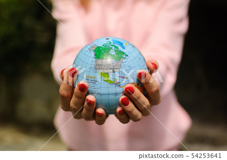 Young female teenager in pink casual clothes with red manicure holding a little globe in her hands Young female teenager in pink casual clothes with red manicure holding a little globe in her hands 54253641