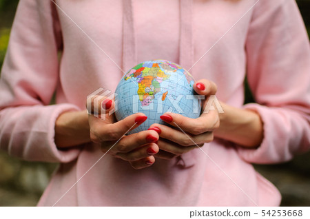 Young woman in pink sweater is holding a little globe in her hands. Eco-friendly concept 54253668