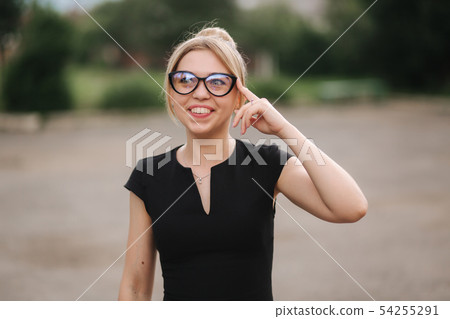 Young attractive female techer in black dress with sunglasses standing outside. Background of school Young attractive female techer in black dress with sunglasses standing outside. Background of school 54255291