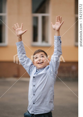 Happy boy jump and raises hands up. Background of school Happy boy jump and raises hands up. Background of school 54255572