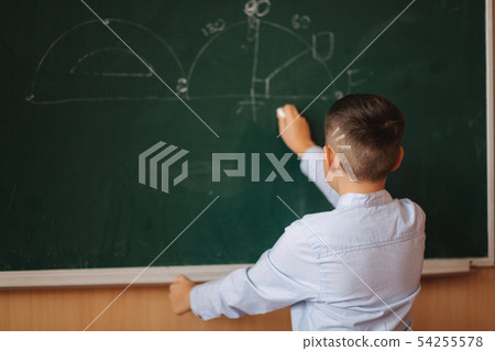 Little boy white down something on blackboard. Clever male 54255578
