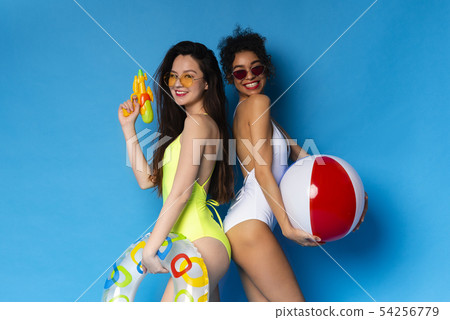 Multiethnic millennial girls enjoying summer vacation with pool party toys Multiethnic millennial girls enjoying summer vacation with pool party toys 54256779