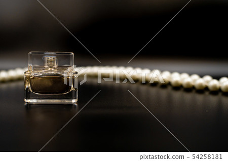 perfume bottle and white beads on black background. perfume bottle and white beads on black background. 54258181