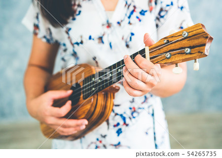 Happy woman musician playing ukulele in studio. Happy woman musician playing ukulele in studio. 54265735