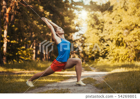 Pretty woman athlete doing exercises before jogging through the woods Pretty woman athlete doing exercises before jogging through the woods 54269801