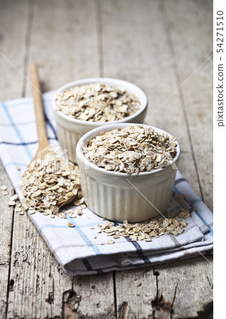 Oat flakes in ceramic bowls and wooden spoon, Oat flakes in ceramic bowls and wooden spoon, 54271510