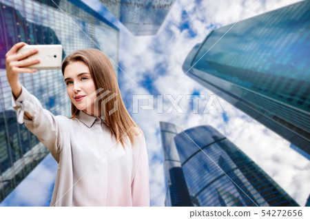 Young girl makes selfie over cityscape background. Young girl makes selfie over cityscape background. 54272656