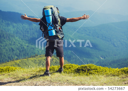 A tourist walks along a mountain meandering trail. Summer walking in mountains A tourist walks along a mountain meandering trail. Summer walking in mountains 54273667