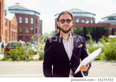 Photo of cheerful man in sunglasses and jacket with laptop standing in city in spring Photo of cheerful man in sunglasses and jacket with laptop standing in city in spring 54274783