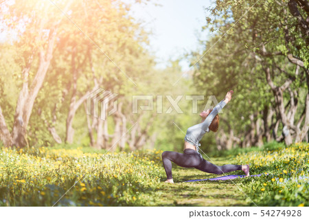 Photo of woman with arms raised practicing yoga in woods during day 54274928