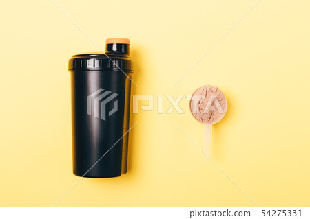 Scoop of whey protein powder near shaker Scoop of whey protein powder near shaker 54275331