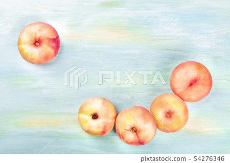 An overhead photo of vibrant organic flat saturn peaches forming a frame, shot from above on a teal An overhead photo of vibrant organic flat saturn peaches forming a frame, shot from above on a teal 54276346