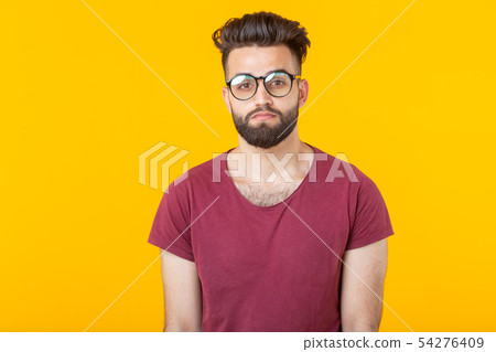 Portrait of a handsome arab young male student in burgundy shirt posing on a yellow background 54276409