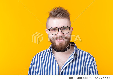 Young positive trendy man hipster with a mustache beard and fetish necklace in shirt posing on a 54276638