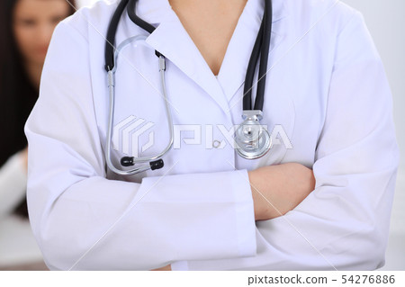 Stethoscope at female doctor breast at hospital office. Unknown physician's hands close-up. Medicine 54276886