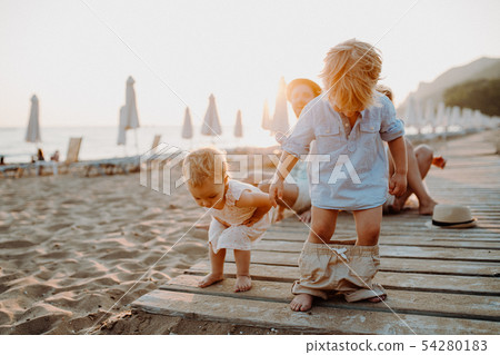 Young family with toddler children having fun on beach on summer holiday. Young family with toddler children having fun on beach on summer holiday. 54280183
