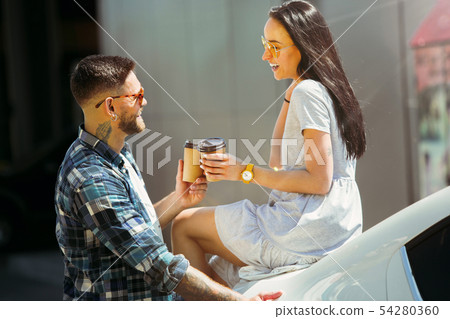 Young couple preparing for vacation trip on the car in sunny day Young couple preparing for vacation trip on the car in sunny day 54280360