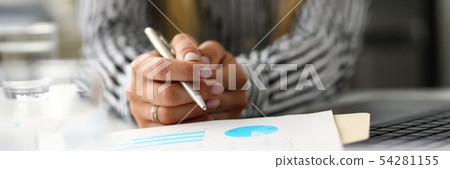 Hands of woman at worktable examining market graphic Hands of woman at worktable examining market graphic 54281155
