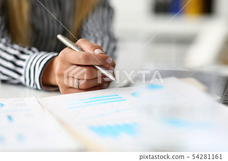 Hands of woman at worktable examining market graphic Hands of woman at worktable examining market graphic 54281161