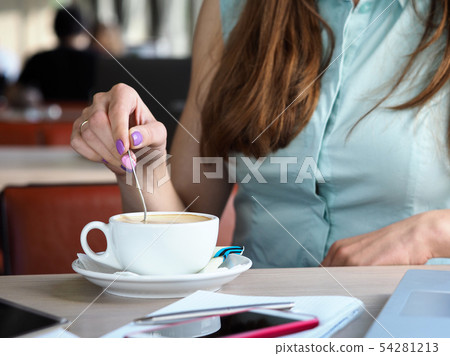 Female hand holding teaspoon stiring coffee in big white cup 54281213