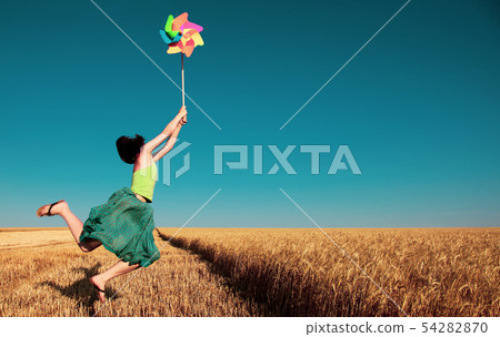 girl jumping with pinwheel over wheat field girl jumping with pinwheel over wheat field 54282870
