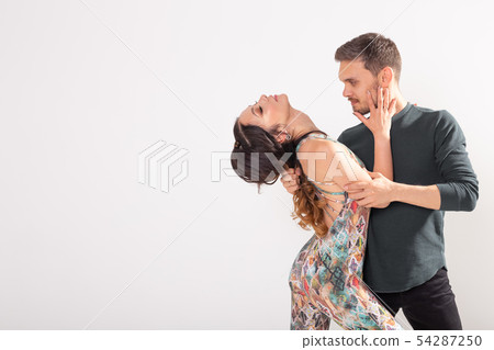 Social dance, bachata, kizomba, tango, salsa, people concept - Young couple dancing over white Social dance, bachata, kizomba, tango, salsa, people concept - Young couple dancing over white 54287250