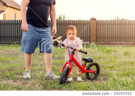 Young father spend time with Cute little one years old toddler girl child and balance bike, father's 54293352
