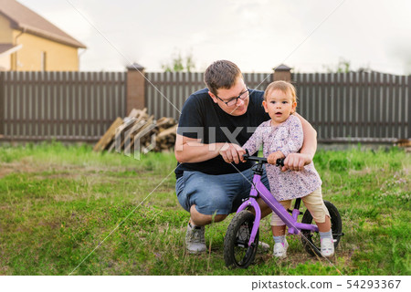 Young father spend time with Cute little one years old toddler girl child and balance bike, father's 54293367