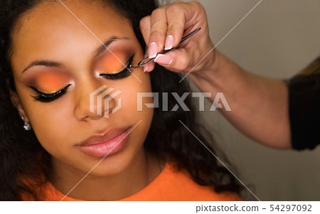 Makeup artist applies makeup on face of girl 54297092