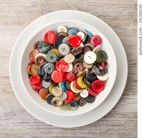 a lot of buttons in dish in wooden background 54298248