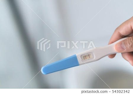 Closeup woman hand holding pregnancy test Closeup woman hand holding pregnancy test 54302342