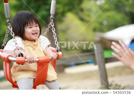 Parent And Child Playing With Swing Stock Photo