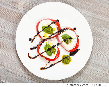 top view of mozzarella, tomato, basil with pesto 54310182