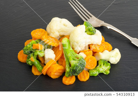 Mix of frozen vegetables on black stone background 54310913