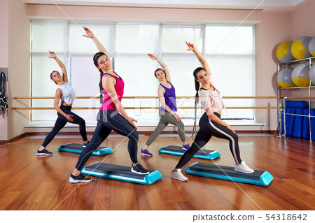 Group of young sporty attractive people practicing yoga lesson with instructor, standing together in Group of young sporty attractive people practicing yoga lesson with instructor, standing together in 54318642
