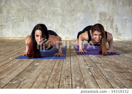 Two smiling beautiful, fitness girls doing exercises in the fitness room give five. Concept sport 54319152