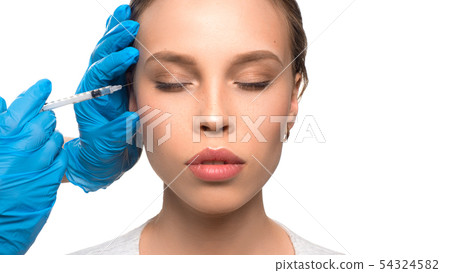 Close up of medical doctor in blue gloves injecting woman in the face with a suringe 54324582