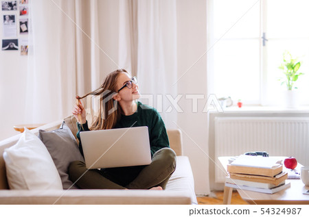 A young female student sitting on sofa, using laptop when studying. A young female student sitting on sofa, using laptop when studying. 54324987