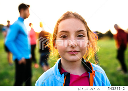 A portrait of small girl with large group of people doing exercise in nature. A portrait of small girl with large group of people doing exercise in nature. 54325142